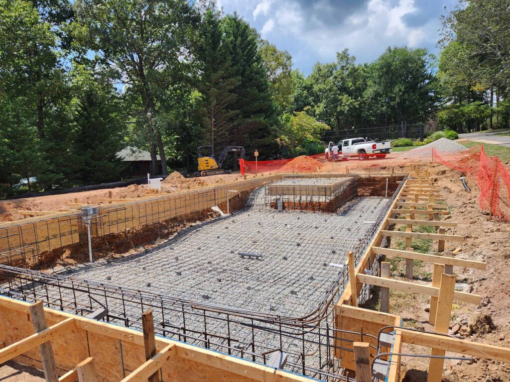 Gunite pool construction showing rebar grid and wood forms installed before concrete is applied at a residential backyard site.